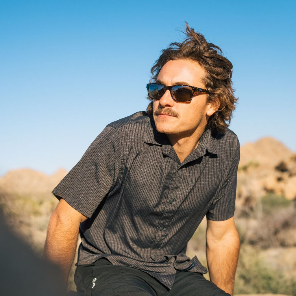 Man in T shirt in Joshua Tree looking to the right wearing sunglasses