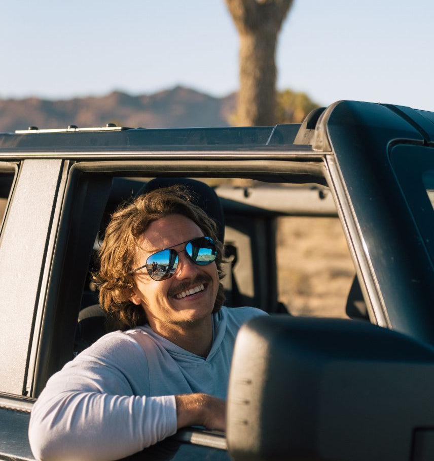 Man with sunglasses leaning out of a car window in a desert setting